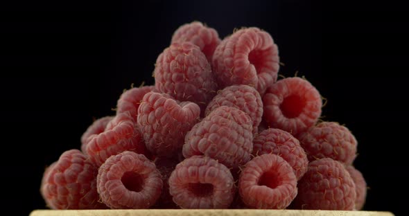 Ripe Raspberry Berries Piled on A Plate, Rotated Against a Black Background