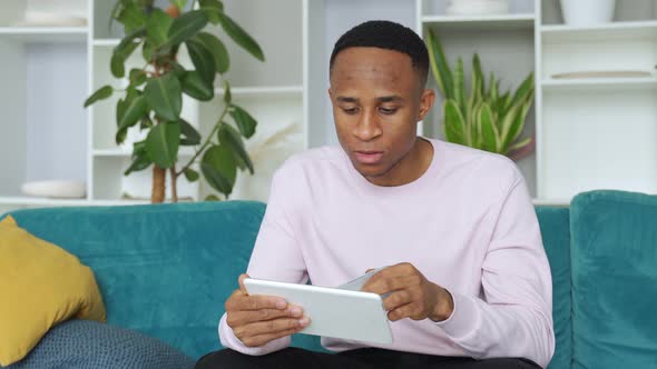 Black Man Smiles Happily, Makes Online Purchases Using a Digital Device, and Makes Online Bank alt