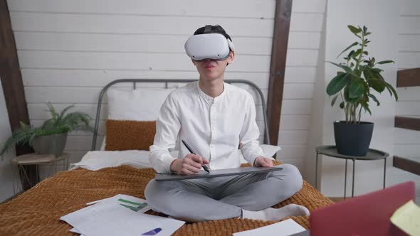 Young Tired Asian Man Sighing Designing Project Using VR Headset and Graphics Tablet alt