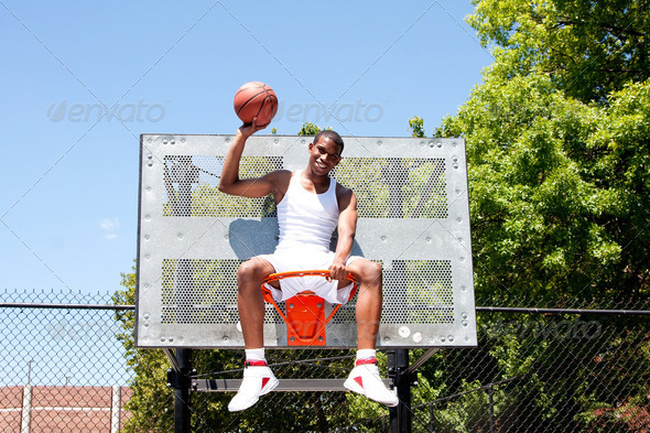 Champion basketball player sitting in hoop - Stock Photo - Images