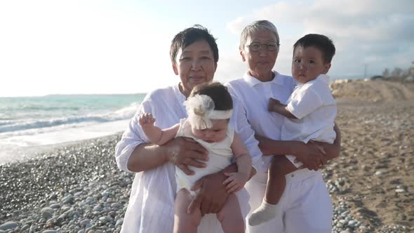 Happy Asian Senior Women Posing with Grandchildren on Picturesque Mediterranean Sea Resort alt