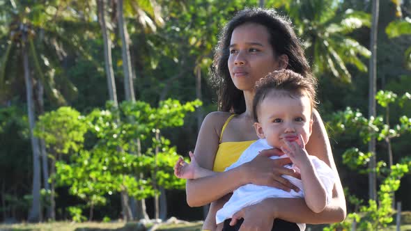 A Young Mother Relaxing and Enjoying the Fresh Air Outdoor with His Little Baby alt