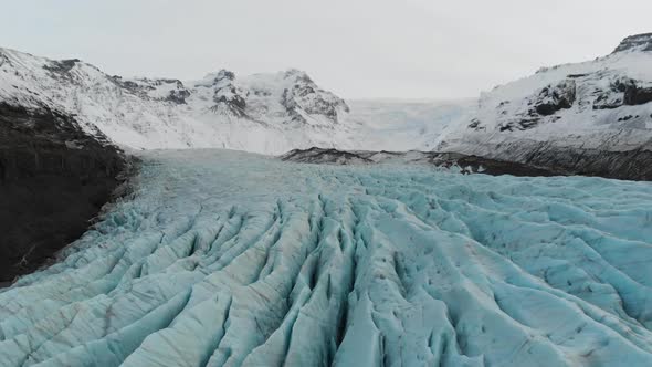 Aerial View of Svinaafellsjokull Glacier, Iceland. Blue Ice Under Volcanic Hills Covered With Snow. alt