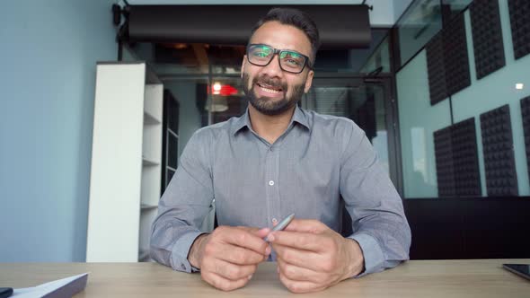 Webcam View of Indian Businessman Talking to Employees in Office Remotely alt