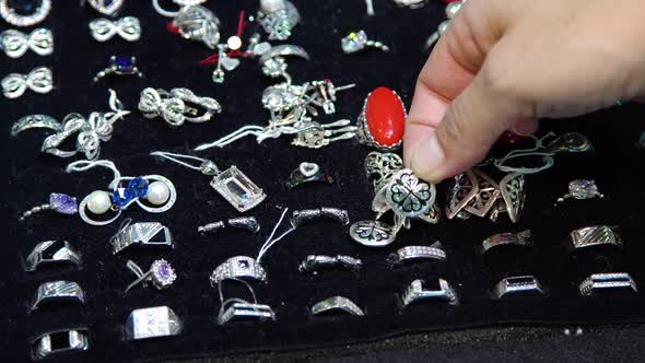 Female Fingers Choosing Jewelry. alt