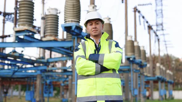 Portrait of Young Smiling Asian Electric Worker With Arms Folded at Power Site