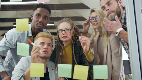 Multiracial Start up Team which Discussing their New Strategy on Transparent Glass Board alt