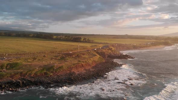 A drone flies over the ocean waves  and into Maui Hawaii's Ho'okipa beach overlook at sunset near Pa alt
