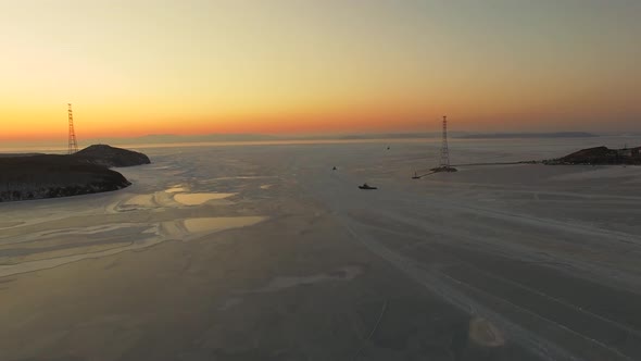 Drone View of the Ice-bound Strait with Tugboats Operating at Sunset alt