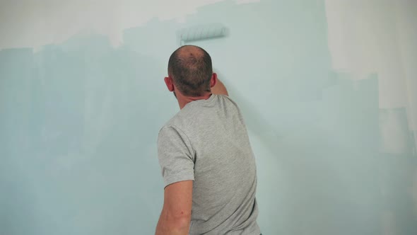 Caucasian Man Paints the Wall with a Roller Dad Makes Repairs in the Room Quality Work Close Up