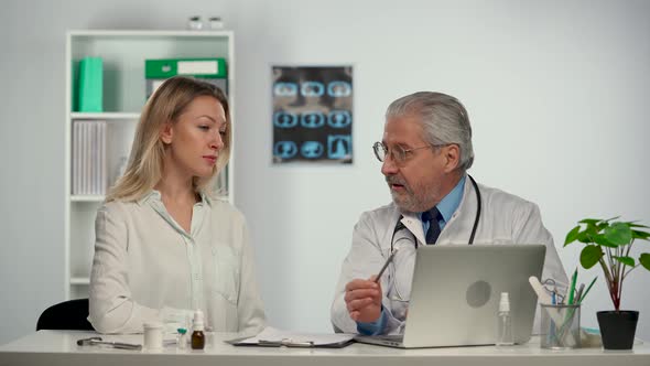 Family Doctor Talks and Displays Information on a Computer During a Patient Consultation at a alt