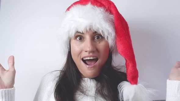 Surprised young Santa woman in a white sweater, Christmas hat