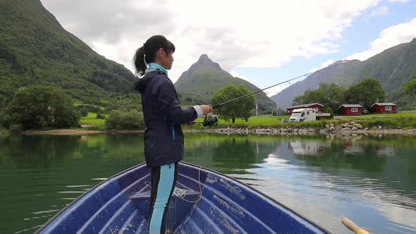 Woman on the Boat Catches a Fish on Spinning in Norway alt
