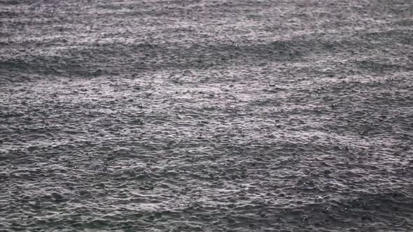 Rain drops falling over a calm, deep ocean. Static medium shot alt