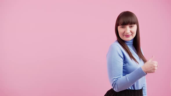 Young Woman Smiling and Standing Made Finger Thumbs Up on the Pink Background Isolated Studio alt