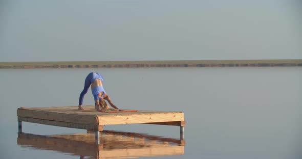 Woman in Sportswear is Doing Yoga in the Middle of the Lake on a Platform alt
