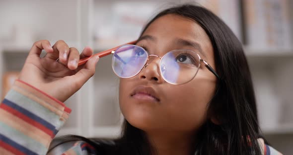 Girl glasses thinking while sitting at classroom alt