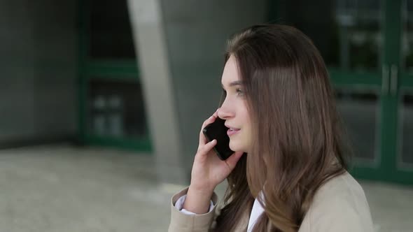 Attractive Girl Outside Talking on Phone, Looking Serious alt