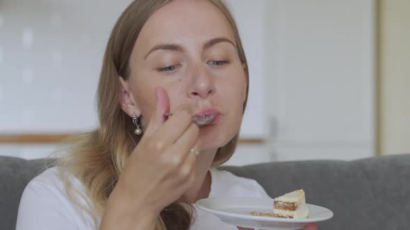 Happy Woman Eating Cake on Kitchen. Lady Enjoying Cake alt