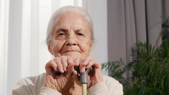 Portrait of Senior Woman Sitting with Cane at Home