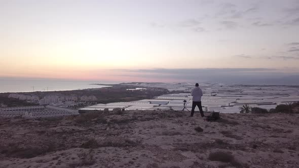 Aerial View Of Man With A Camera On Top Of A Cliff looking the sunset alt