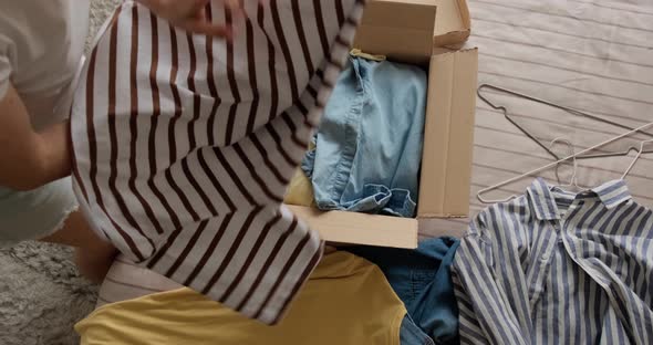 Woman packing used clothes into box to resell on the internet alt