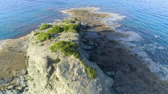 Aerial Top View of Cliff Rocks in a Blue Sea alt