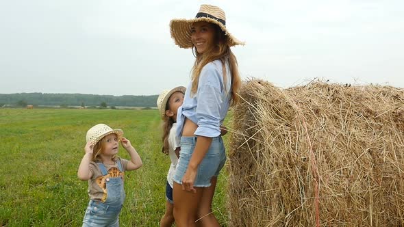 Happy Family, Mother and Her Adorable Children Walking on the Fields With Haystacks