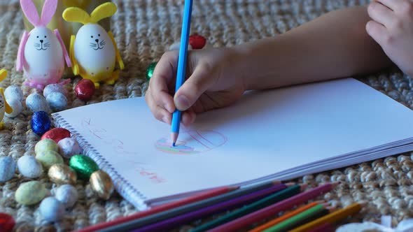 A child draws in a notebook for the Easter holiday with Easter decorations in the background
