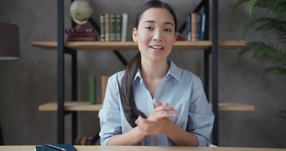Smiling Young Asian Woman Teacher Conducts Online Lesson Looking at Camera alt