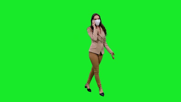 Young Stylish Woman in Mask Talking on Smartphone against Green Screen 