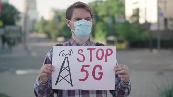 Portrait of Caucasian Man with Stop 5G Banner Standing on Urban City Street. Serious Male alt