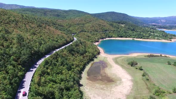 Aerial view of red van driving by artificial lake Peruca, Croatia alt