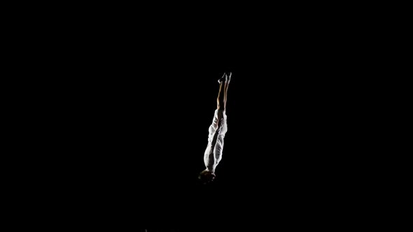 Beautiful Male Gymnast in White Doing Acrobatic Stunts on Black Background in Slow Motion, Rotation alt