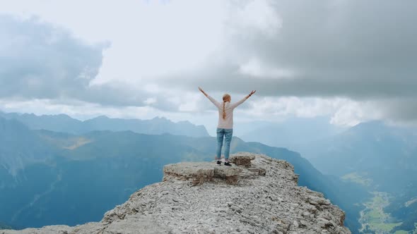 Young Woman with Outstretched Arms Enjoying the Beauty of Nature on Mountain Rock alt