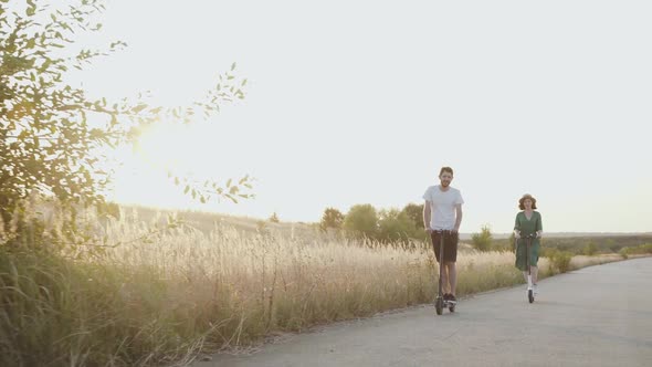 Happy Young Couple in Love Riding on Electric Scooters with Joy on Road alt