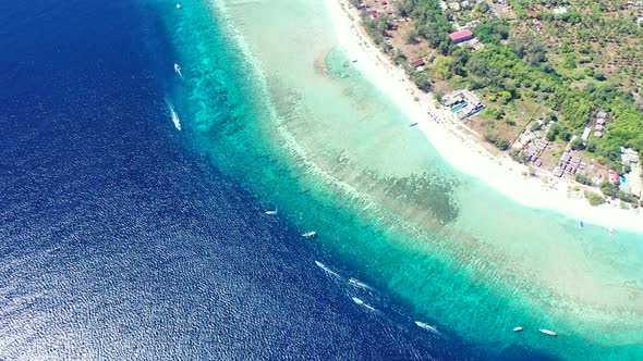 a beautiful Balinese island surrounded by boats in crystal clear waters. alt