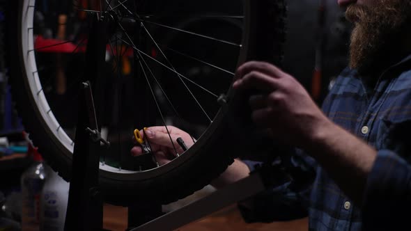 Tracking Shot of Skilled Bike Mechanic Fixing Spokes Using Tool to Tension Spokes in Rim of Bicycle alt