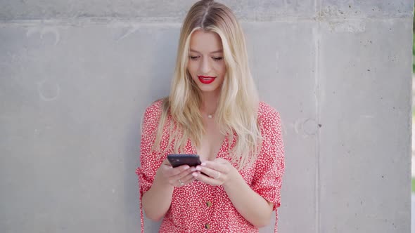 Glad Female Using Cellphone Near Wall alt