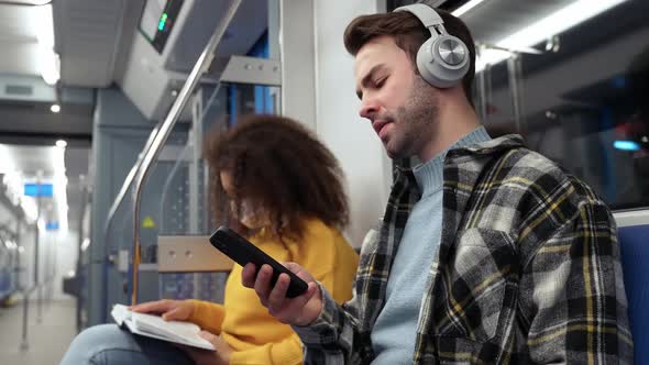 Students Go to Study in the Subway Young Man Uses a Smartphone and Listens to Music with Wireless alt