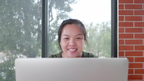 Happy Asian woman in casual suit video call with family in laptop alt