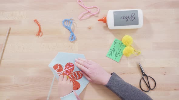 Flat lay. Little girl learning how to sew with her mother at the craft table. alt