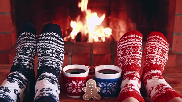 Couple In Christmas Socks Near Fireplace. Friends Having Fun Together