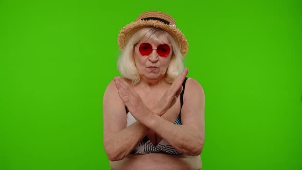 Mature Woman Traveler in Red Sunglasses Showing Stop Sign Dislike Gesture Bad Idea Wrong Choice alt