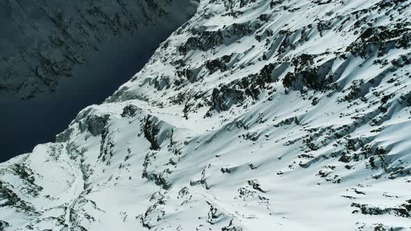 Flight Over Rocky Alpine Mountains Valley Full Of Snow