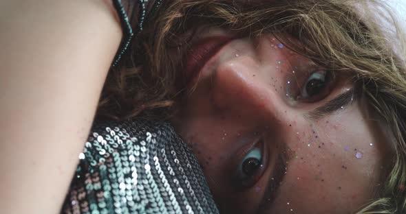 Close up of a glitter girl’s face while she is sitting on the floor alt