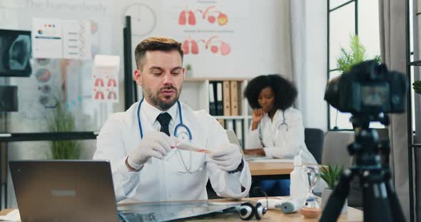 Doctor Telling Online Viewers Through Camera How Correct is to Use Disposable Syringe alt