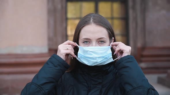 Woman Putting on Medical Mask for Coronavirus Protection Outdoors