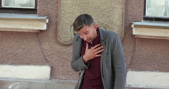 Charismatic Man Coughing Strongly and Spraying Nose with Nasal Spray on Street alt