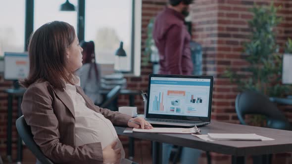 Close Up of Pregnant Woman Holding Hand on Belly Working on Business Strategy alt